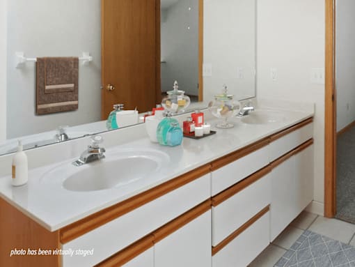 A bathroom with a white counter top and a white sink.