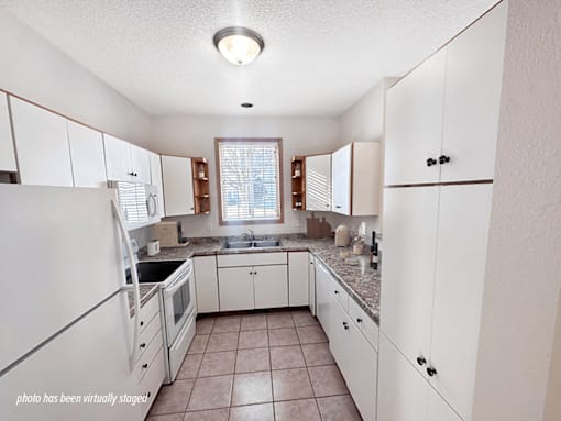 A kitchen with white cabinets and a tiled floor.