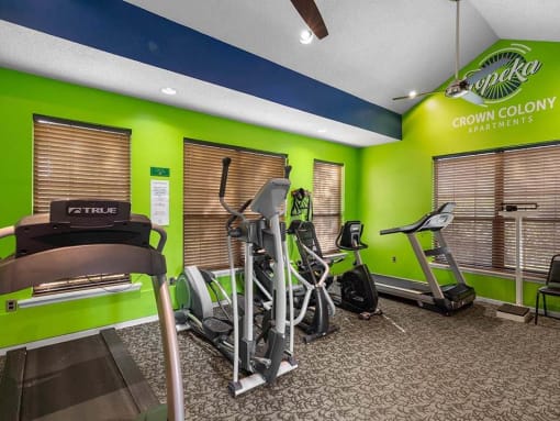 the gym is equipped with cardio equipment and green walls