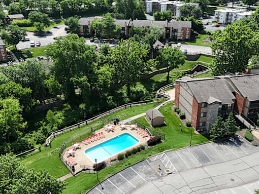 A pool surrounded by trees and a grassy area.