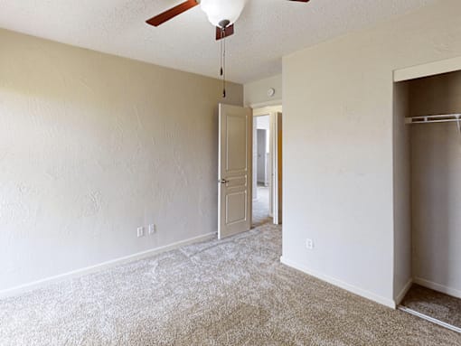 A room with a ceiling fan and a doorway leading to another room.