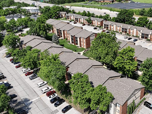 Apartment complex with a parking lot in front.