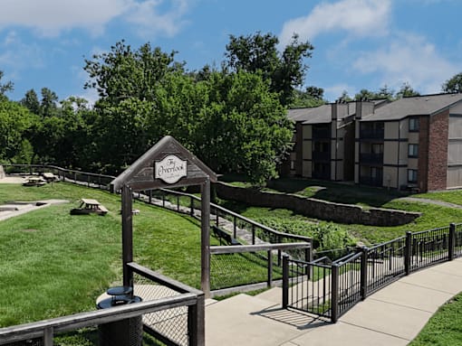 A large green space with trees and apartments in the background.