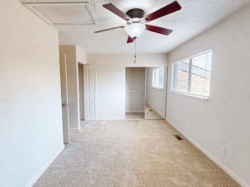 A room with a ceiling fan and carpeted floor.