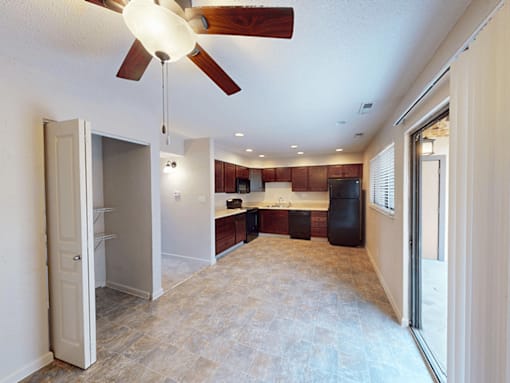 A kitchen with a refrigerator, sink, and cabinets is visible from the living room.