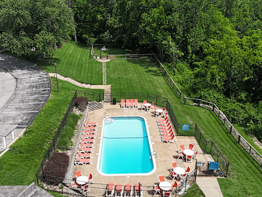A pool surrounded by a fence and chairs.