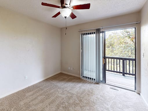 A room with a ceiling fan and carpeted floor.