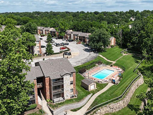 A large apartment complex with a pool and a stone wall.