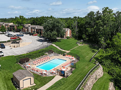 A pool surrounded by trees and a grassy area.