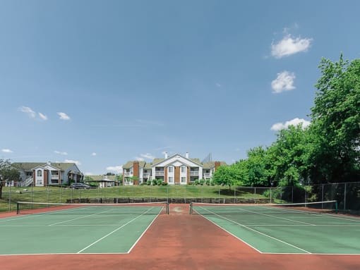 a tennis court with apartments in the background