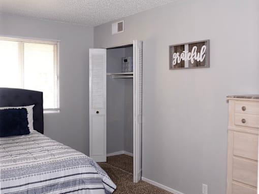 A bedroom with a bed, dresser, and a closet with a sign that says