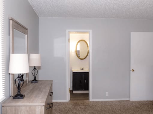 A room with a white door and a mirror on the wall.