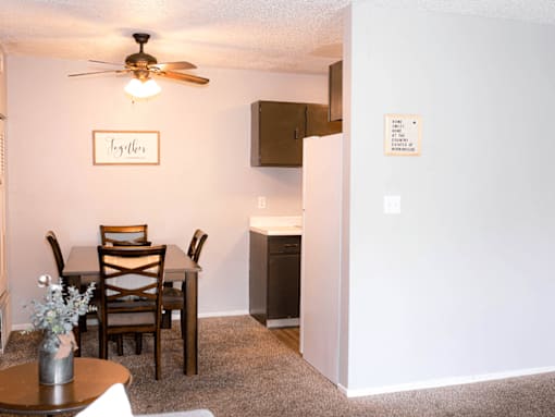 A dining room with a table set for two and a framed sign that says