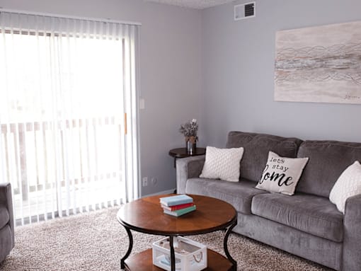 A living room with a grey couch and a round table with a book on it.