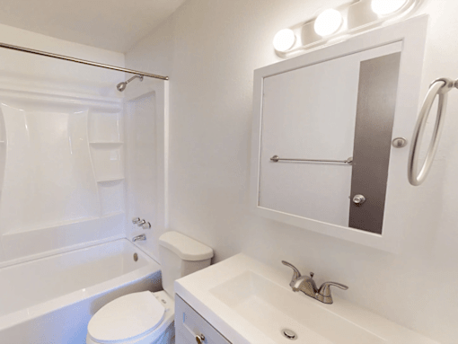 A white bathroom with a toilet, sink, and shower.