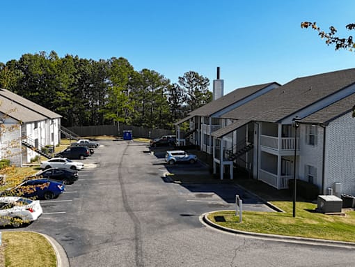 a view of a street with houses and cars in a parking lot