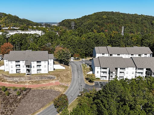 an aerial view of an apartment complex with a road and trees