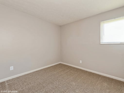 apartment bedroom with carpet and a window