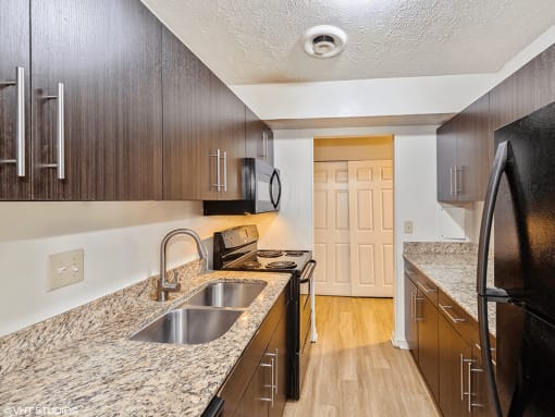apartment kitchen with wood cabinets and granite counter tops and a sink