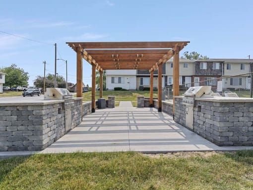 a stone walkway with a wooden pergola