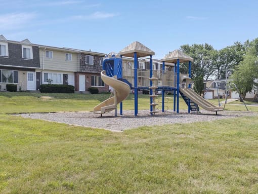 a playground with a slide and plently of grassy area to play around