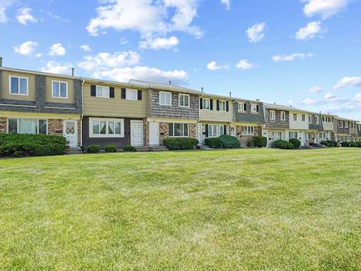 A row of houses with green lawns in front.