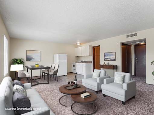 A living room with a grey couch, a coffee table, and a dining table with chairs.