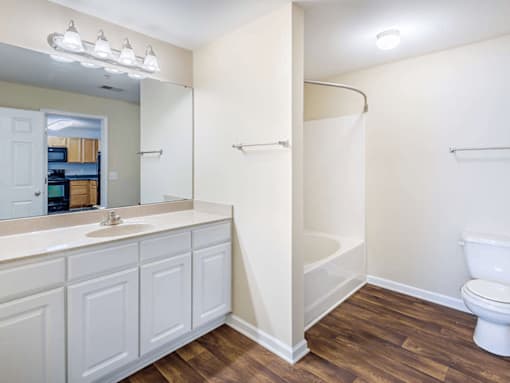 Primary bathroom with bright vanity and wood style flooring