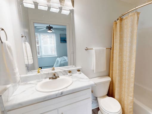 A bathroom with a white counter top and a white toilet.