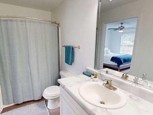 A bathroom with a white sink, toilet, and shower curtain.