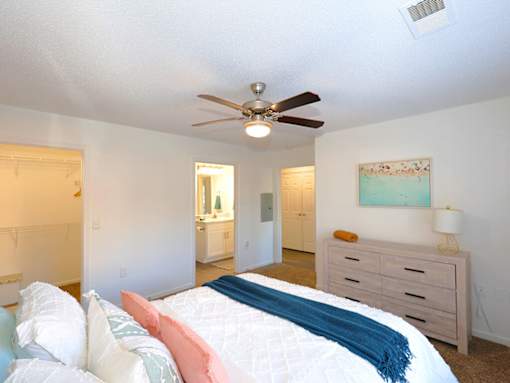 A bedroom with a bed, dresser, and ceiling fan.