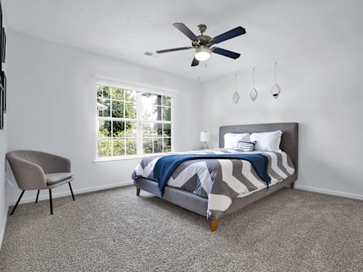 Apartment bedroom with a bed, window, and ceiling fan