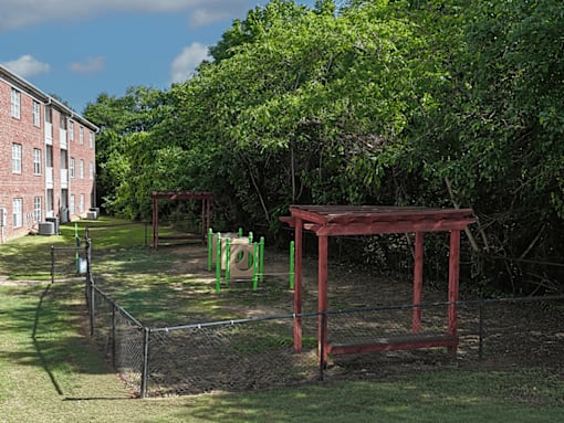 A playground with a red swing set and green slide.