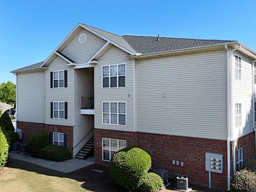A two-story apartment building with a red brick base and beige siding.