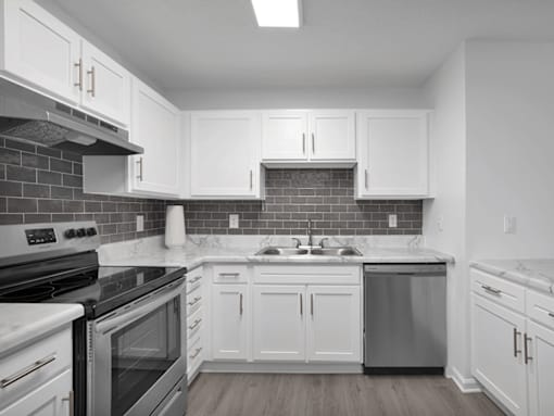 Apartment kitchen with white cabinets and a black stove top oven