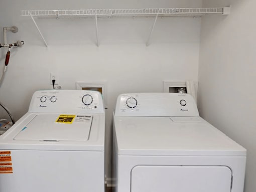 Two white front loading washing machines in a laundry room.