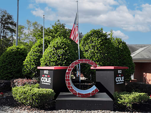 A sign for Cole Apartments is displayed in front of a building.
