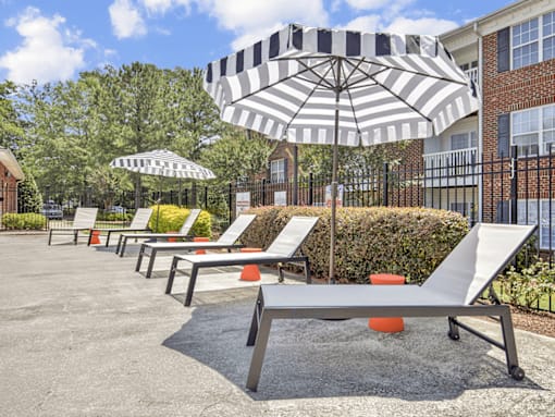 A row of sun loungers are arranged in a row under umbrellas.