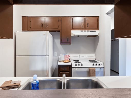 a kitchen with white appliances and wooden cabinets and a double bowl sink