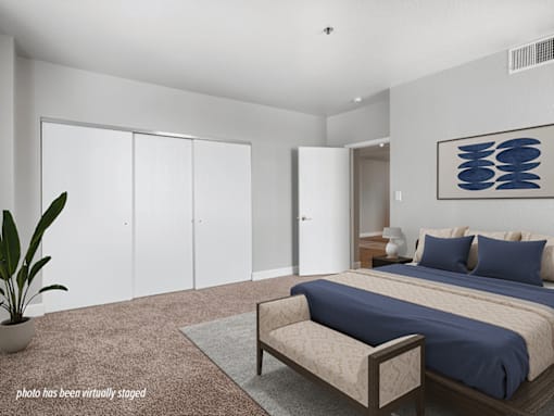 A bedroom with a bed, a bench, and a plant.