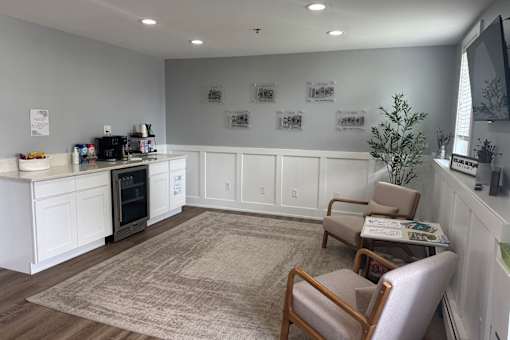 A white kitchen with a rug on the floor and two chairs.