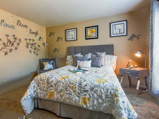 A bedroom with a bed, nightstand, and wall decorations.