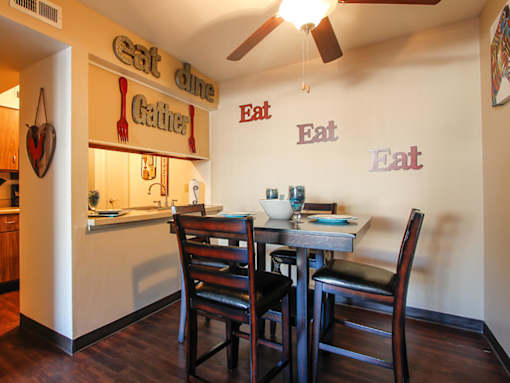 A dining area with a table set for two and a sign that says eat dine gather.