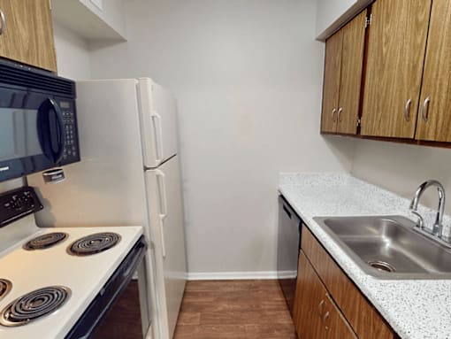 A kitchen with a stove, refrigerator, microwave, and cabinets.