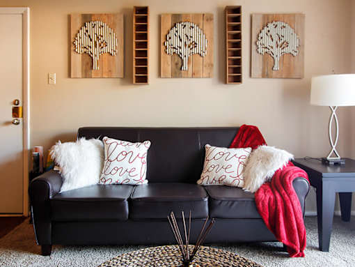 A black couch with a red blanket and pillows with the word love on them.