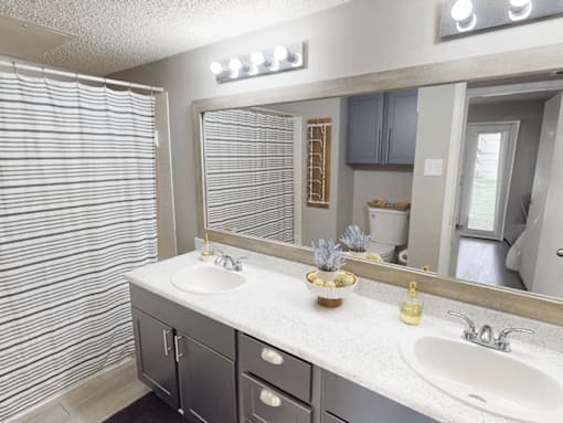 A bathroom with a sink, mirror, and a vase of flowers.