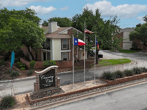 A sign for the Country Club Villas is in front of a building.