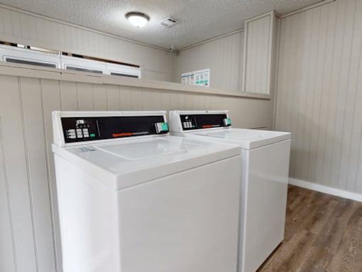 Two white front loading washing machines in a laundry room.