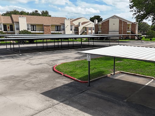 A parking lot with a red curb and a white building in the background.