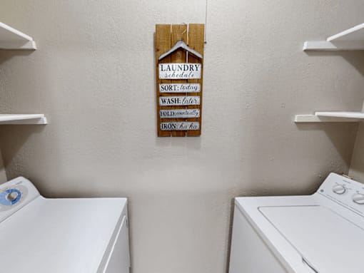 Laundry sign hanging on a wall above a washer and dryer.